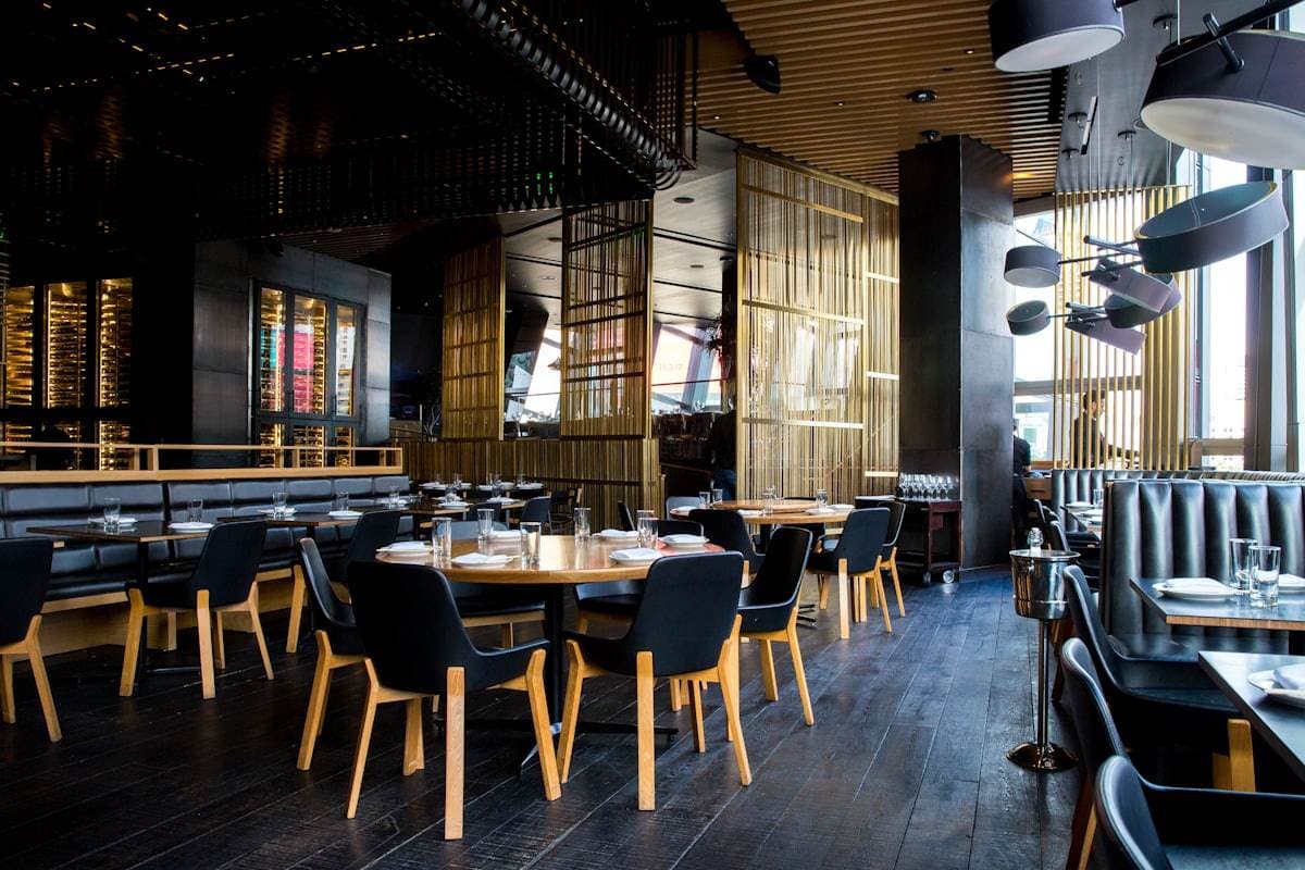 An empty upscale restaurant dining room with set tables, leather booths, and pendant lights before service